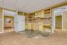 Kitchen featuring a drop ceiling, light carpet, freestanding refrigerator, light brown cabinetry, and light countertops