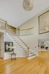 Stairway with a high ceiling, wood finished floors, arched walkways, and a warm lit fireplace