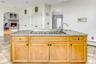 Kitchen featuring light tile patterned floors, arched walkways, an island with sink, light brown cabinets, and open floor plan