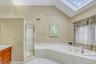 Bathroom featuring a skylight, a bath, a shower stall, light tile patterned floors, and lofted ceiling