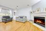 Living area with a tiled fireplace, light wood-style flooring, and a baseboard radiator
