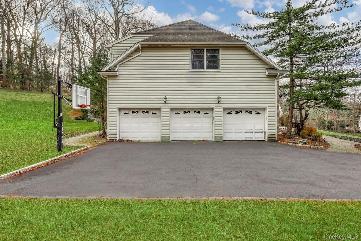 View of side of property featuring a yard, driveway, and a shingled roof