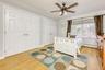 Bedroom with light wood finished floors, two closets, baseboard heating, and ceiling fan