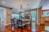 Sophisticated open-concept dining area, perfectly positioned right next to a cozy rustic red brick fireplace and mantel.