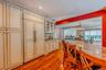 Kitchen featuring integrated paneled refrigerator, built-in cabinetry with glass-front uppers, polished wood-finish flooring, and a curved island with