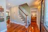 Warm and inviting entry foyer showcasing stunning gleaming hardwood floors, a beautiful wood-rail staircase, and an open layout that leads seamlessly 