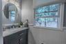 Chic 1st-floor powder room with custom beadboard wainscoting, modern vanity, and bright natural light.
