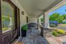 Beautiful covered front porch with custom stone pillars, premium pavers, and an elegant glass entryway.