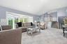 Spacious living area featuring a large bay window with outdoor views, recessed lighting, light-toned carpeting, and a staircase with wood railings