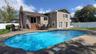 Outdoor swimming pool with a surrounding paver patio and a neutral-toned siding exterior