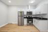Modern kitchen featuring white cabinetry, dark countertops, and stainless steel appliances including a refrigerator, range, and microwave