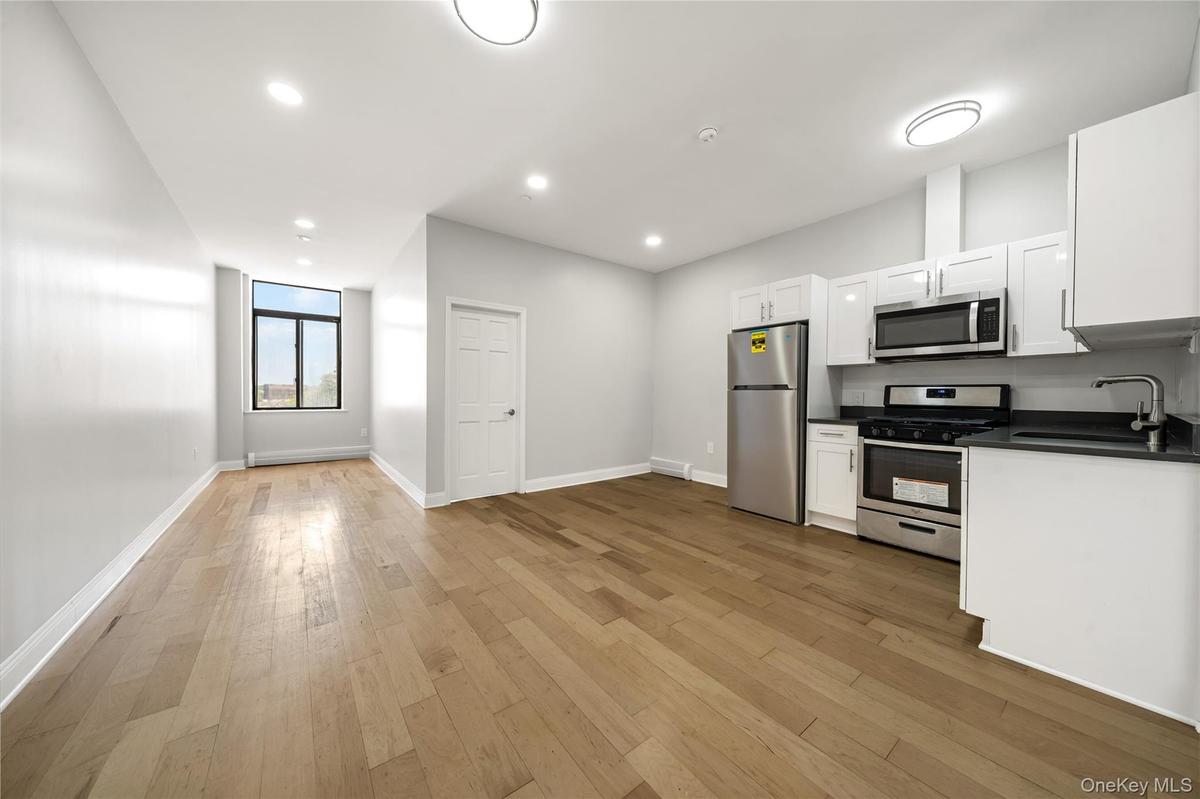 Open-concept living space featuring wood-finish flooring, recessed lighting, and a modern kitchen
