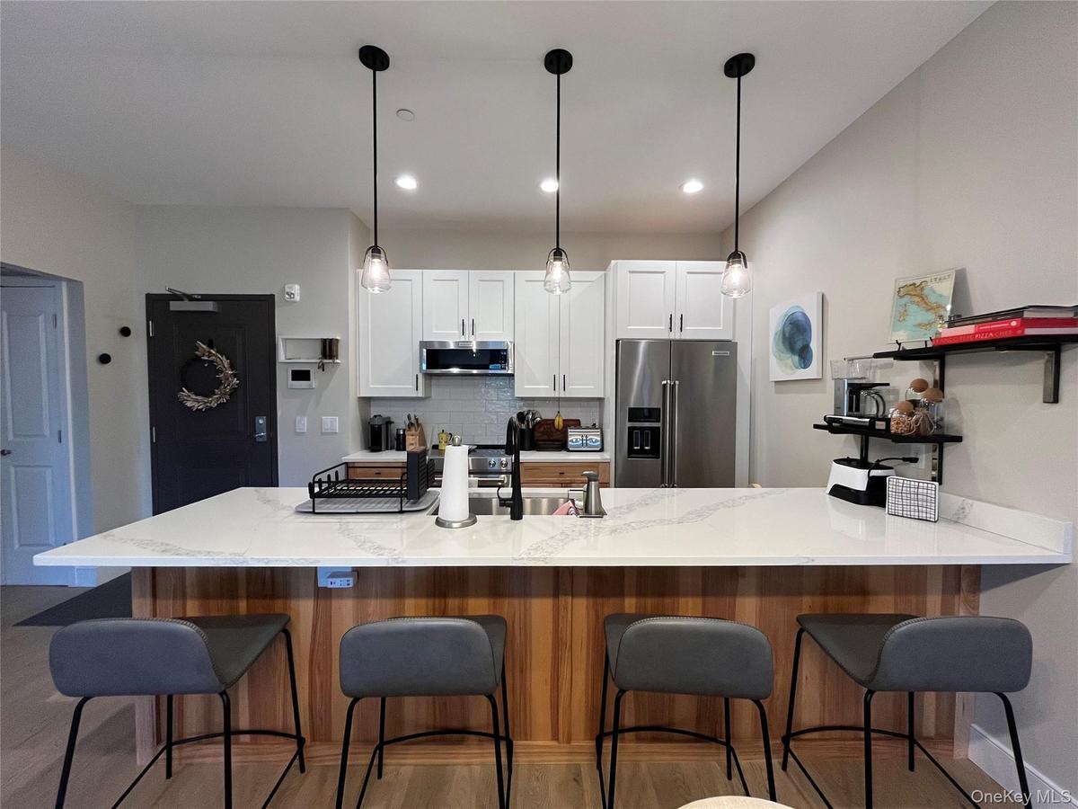 Kitchen island featuring a granite countertop, wood-finish paneling, and three pendant lights