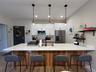 Kitchen island featuring a granite countertop, wood-finish paneling, and three pendant lights