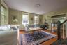 Living room with baseboard heating, wood finished floors, and wainscoting