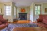 Living room featuring wood finished floors, healthy amount of natural light, a fireplace, ornamental molding, and a wainscoted wall