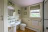 Bathroom with a baseboard radiator, wood finished floors, a wainscoted wall, and crown molding