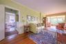 Living area with wood finished floors, plenty of natural light, a baseboard heating unit, crown molding, and wainscoting