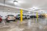 Underground parking garage featuring concrete flooring, white walls, yellow support columns, and overhead lighting fixtures