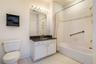 Bathroom featuring a white vanity with dark countertop, an integrated sink, and an overhead strip light fixture