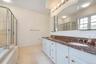 Double vanity with integrated sinks, granite countertop, and white cabinetry