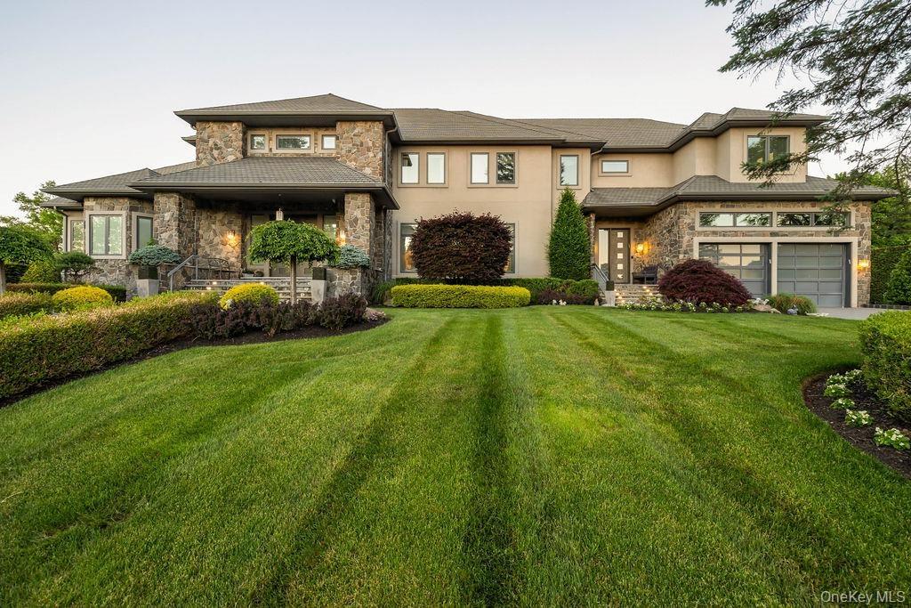Stately multi-level residence featuring a stone and stucco facade, a prominent covered entry, and a two-car garage with frosted glass panels