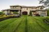 Stately multi-level residence featuring a stone and stucco facade, a prominent covered entry, and a two-car garage with frosted glass panels