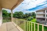 Private balcony featuring a neutral-toned concrete surface, cream-colored metal railings, and an overhead soffit