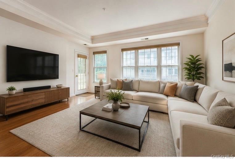 Spacious living area featuring wood-finish flooring, recessed lighting, and a tray ceiling with crown molding