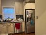 Kitchen featuring light-toned cabinetry, a stainless steel dishwasher, a stainless steel refrigerator, and a dark tile backsplash