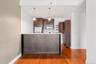 Kitchen island with a light-toned countertop, wood-finish flooring, dark wood cabinetry, stainless steel appliances, and pendant lighting