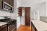 Kitchen featuring stainless steel appliances, dark wood-finish cabinetry, light-toned countertops, a white subway tile backsplash, and wood-finish flo