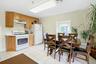 Kitchen with white appliances, light countertops, light tile patterned flooring, and under cabinet range hood