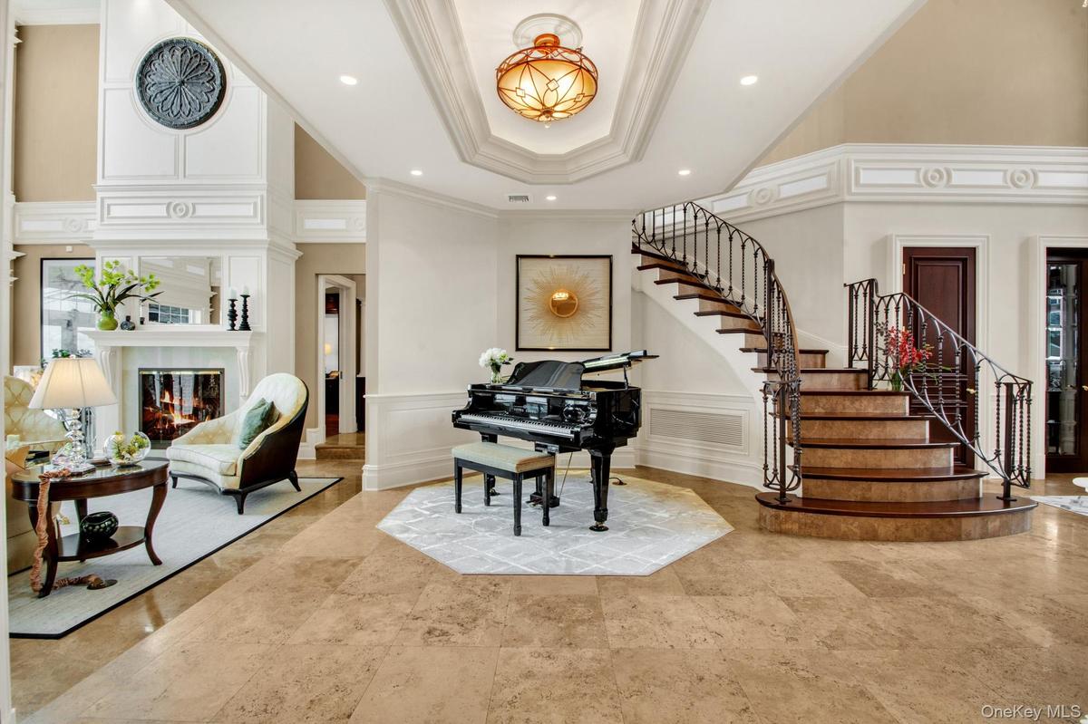Foyer featuring a decorative wall, a glass covered fireplace, ornamental molding, a tray ceiling, and a towering ceiling