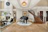 Foyer featuring a decorative wall, a glass covered fireplace, ornamental molding, a tray ceiling, and a towering ceiling