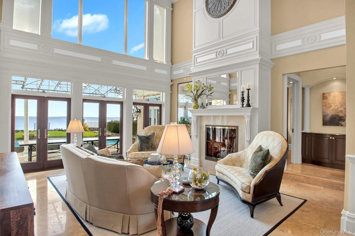Living room featuring a water view, a towering ceiling, french doors, and a premium fireplace