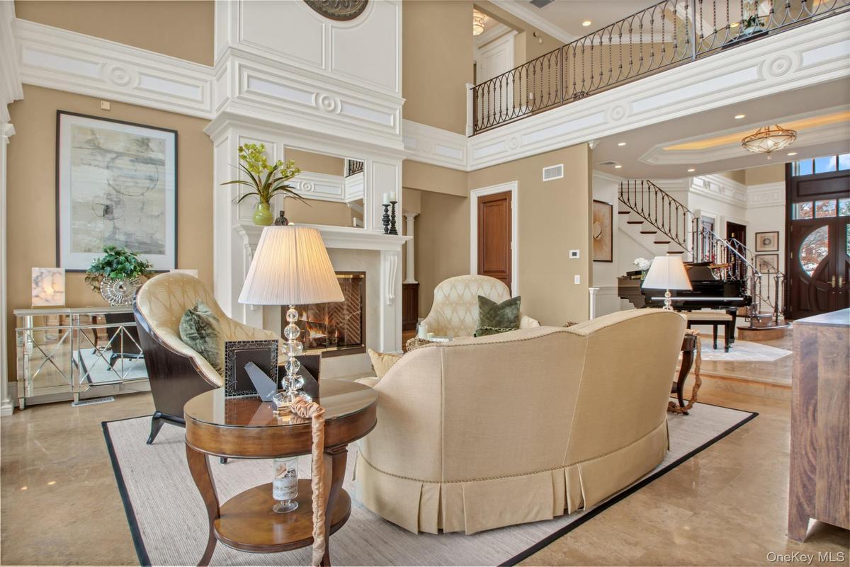 Living area with a towering ceiling, a lit fireplace, stairs, and crown molding