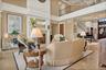 Living area with a towering ceiling, a lit fireplace, stairs, and crown molding