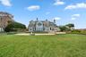 Back of house featuring a chimney, french doors, a patio area, an outdoor fire pit, and a balcony
