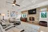 Living room with a stone fireplace, beamed ceiling, a ceiling fan, and coffered ceiling