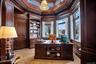 Office area featuring crown molding, built in features, a towering ceiling, and wood walls