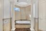 Bathroom with tile walls, a bath, ornate columns, and crown molding
