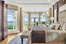 Bedroom featuring french doors, crown molding, a water view, light wood-type flooring, and a tray ceiling