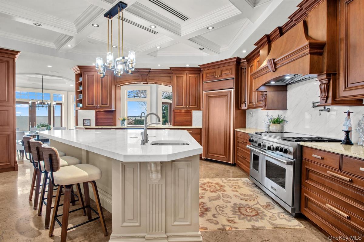 Kitchen with pendant lighting, a chandelier, high end appliances, open shelves, and light stone counters