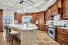 Kitchen with pendant lighting, a chandelier, high end appliances, open shelves, and light stone counters