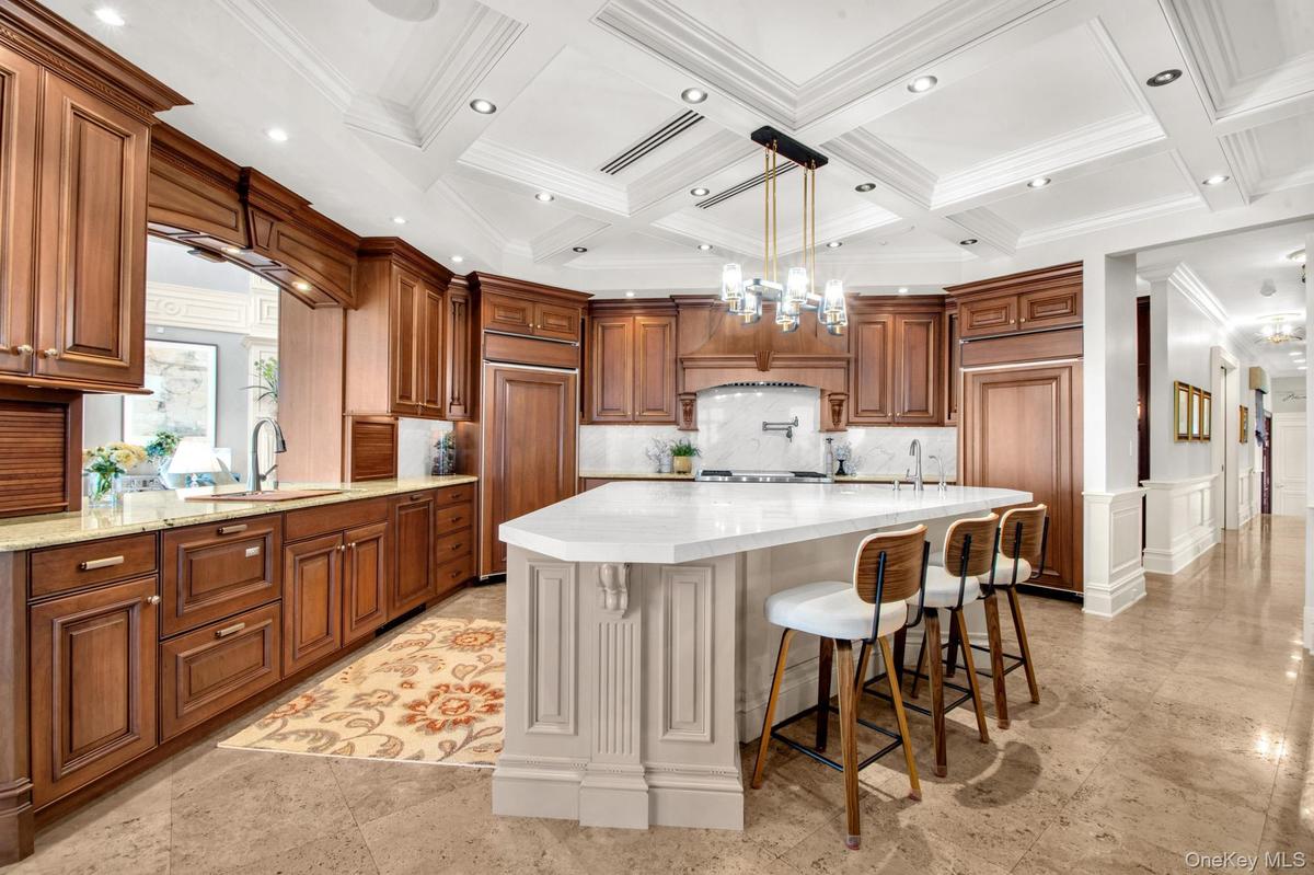 Kitchen featuring a chandelier, brown cabinetry, a kitchen bar, pendant lighting, and light stone counters