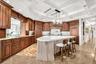 Kitchen featuring a chandelier, brown cabinetry, a kitchen bar, pendant lighting, and light stone counters