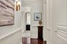 Hallway with crown molding, dark wood-style floors, wainscoting, and a decorative wall
