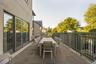 Expansive outdoor terrace featuring large format stone tile flooring, a dark metal railing, and multiple sets of glass panel doors