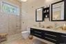 Spacious bathroom featuring a dual vanity with vessel sinks, a large shower with mosaic tile, pebble flooring, and a transom window